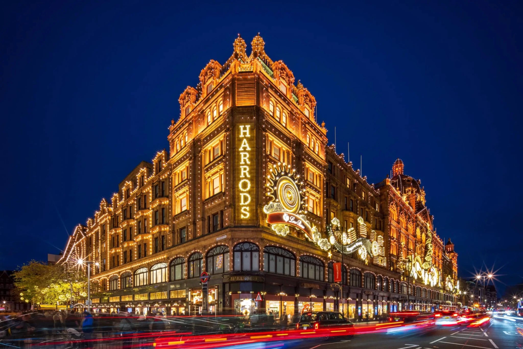 Harrods department store illuminated at night with light trails and clear dark blue sky