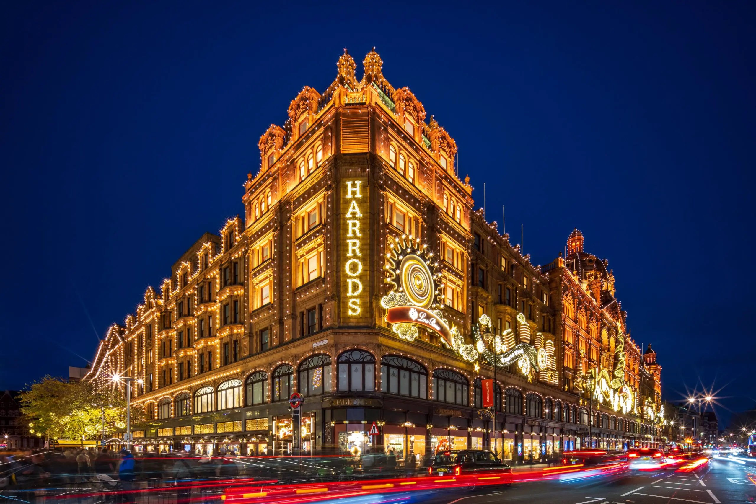 Harrods department store illuminated at night with light trails and clear dark blue sky
