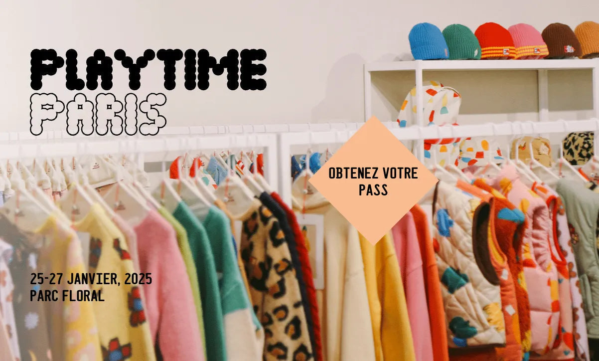 Colorful children's sweaters, vests, and hats on racks at Playtime Paris kids fashion event