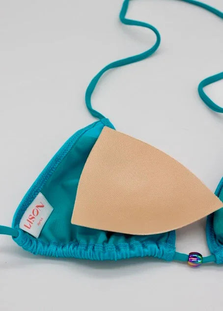 Close-up of turquoise triangle bikini top with removable beige padding and Lison Paris tag