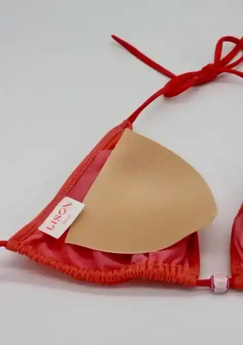 Close-up of coral and gold girls' triangle bikini top with removable padding on white background