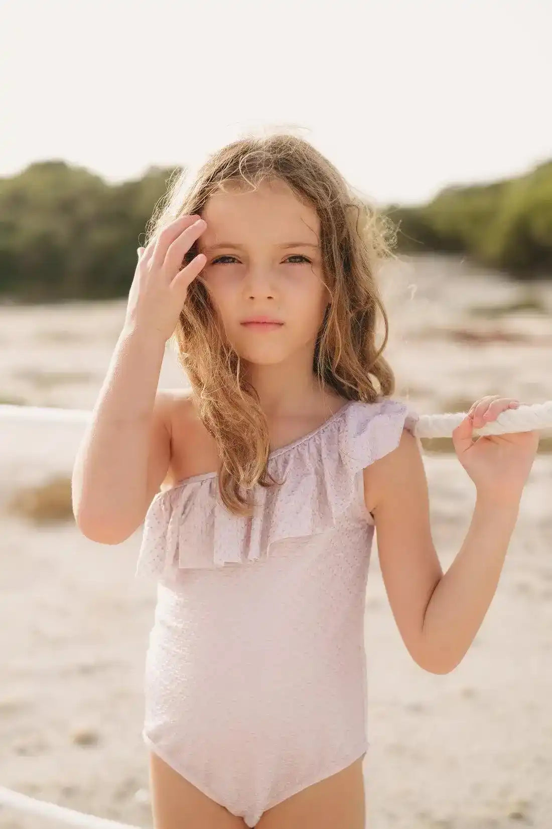 Girl wearing pink asymmetrical ruffle swimsuit on a sunny beach