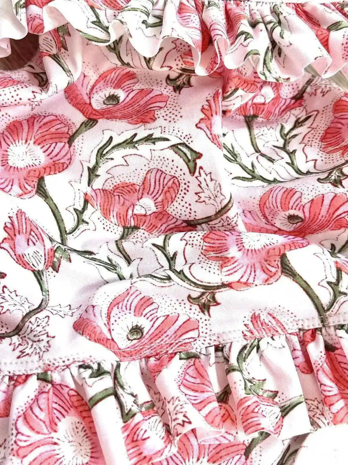 Pink floral ruffle detail on baby girl one-piece swimsuit fabric close-up