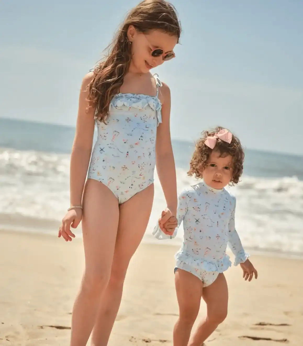 Girls wearing Lison Paris one-piece UV swimwear on the beach, recycled fabric, summer vacation