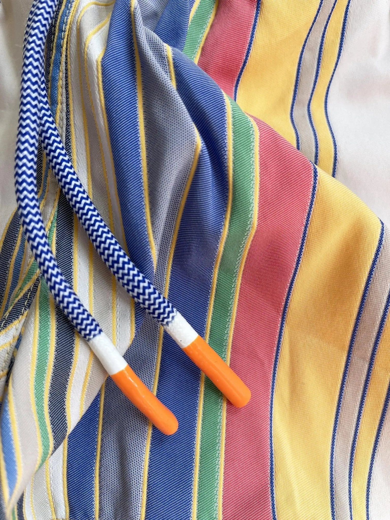 Close-up of multicolored striped boys' swim shorts with blue and white drawstring