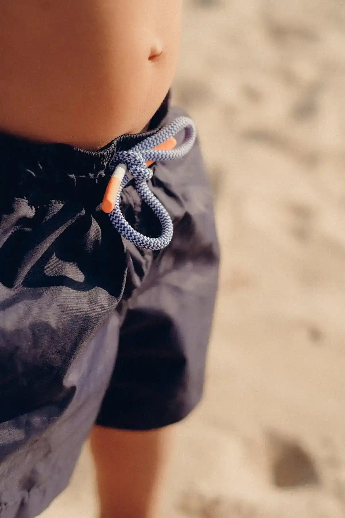 Navy boys' swim trunks with drawstring at the beach
