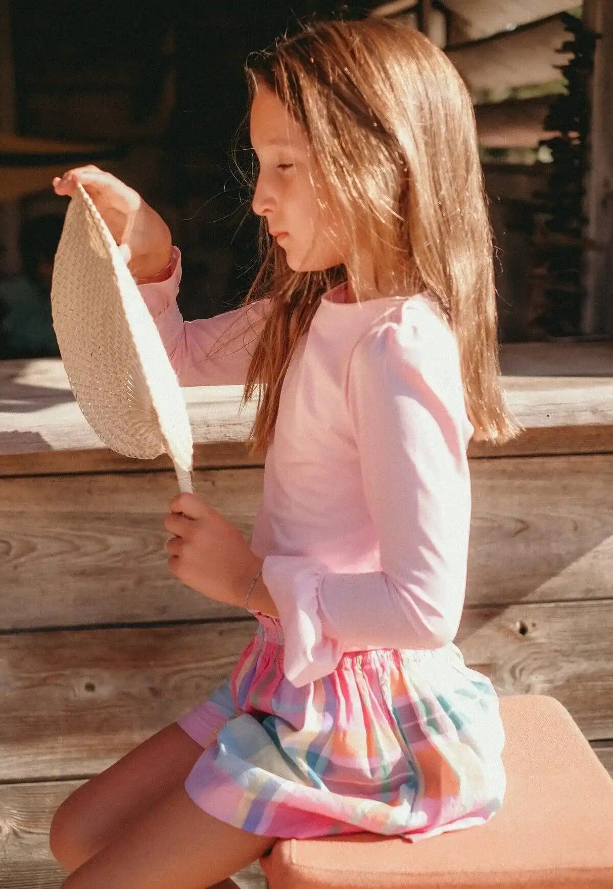 Girl wearing Lison Paris pink UPF 50+ anti-UV swim shirt and colorful skirt outdoors