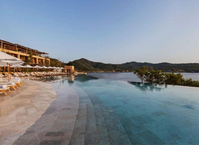 Luxury infinity pool with sun loungers overlooking scenic lake and mountains at resort
