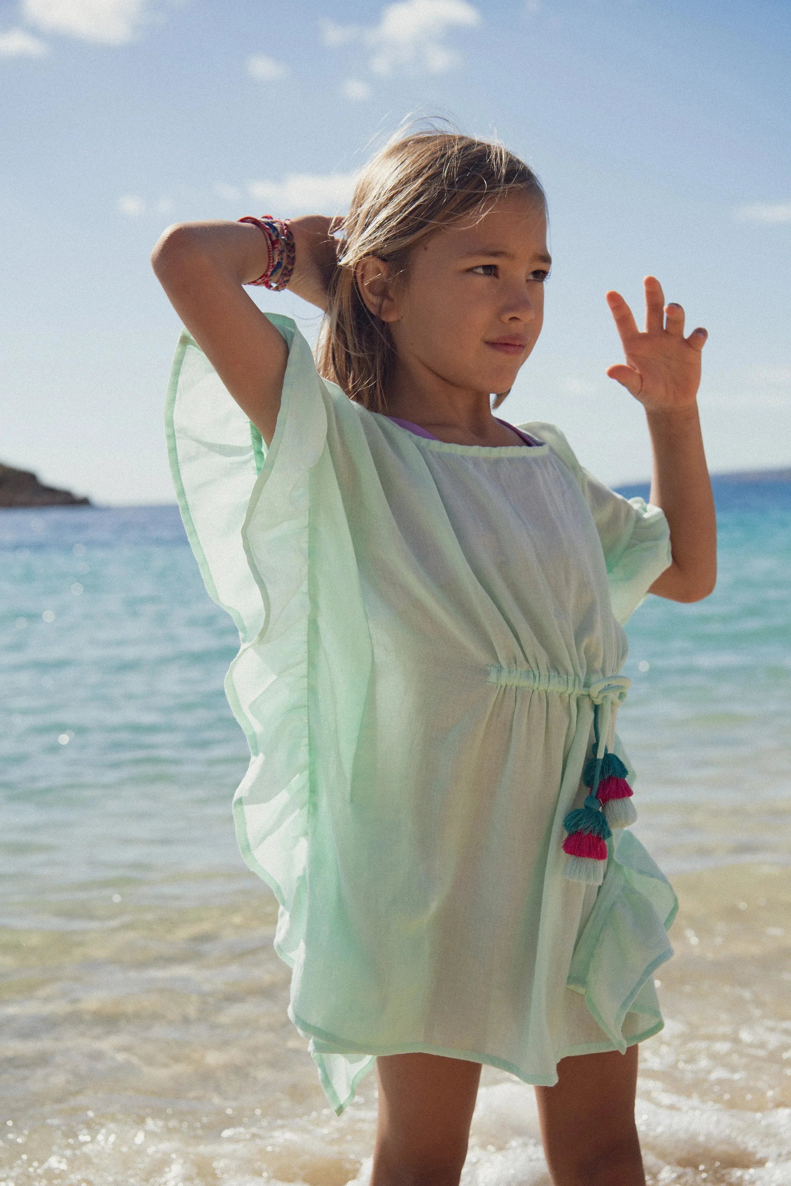 Girl in aqua beachwear kaftan with tassels by the sea, Lison Paris summer collection