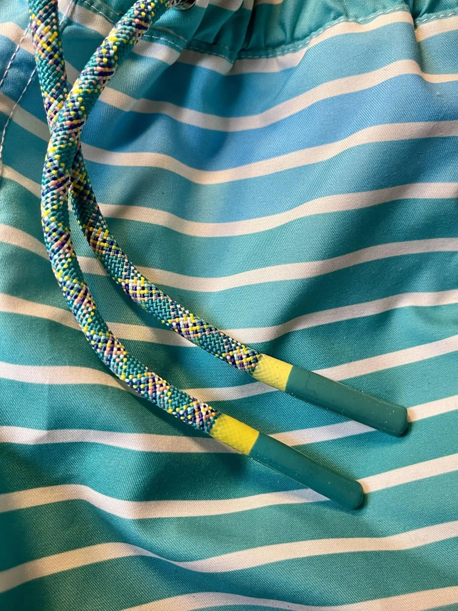 Close-up of blue and white striped boys' swim shorts with multicolor drawstring.